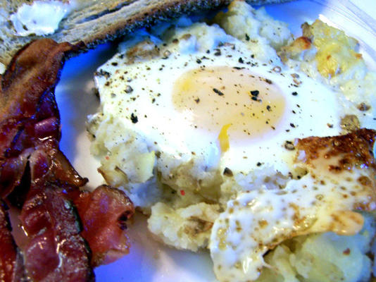 œufs au four sur un lit de pommes de terre avec du bacon